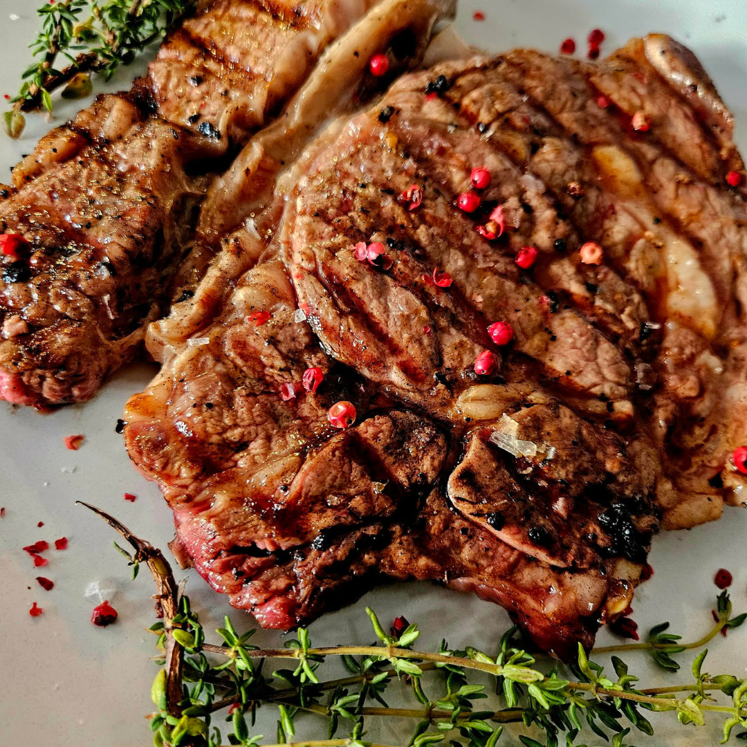 Grilled beef steak seasoned with herbs and pink peppercorns, served as an elegant wedding catering main course.
