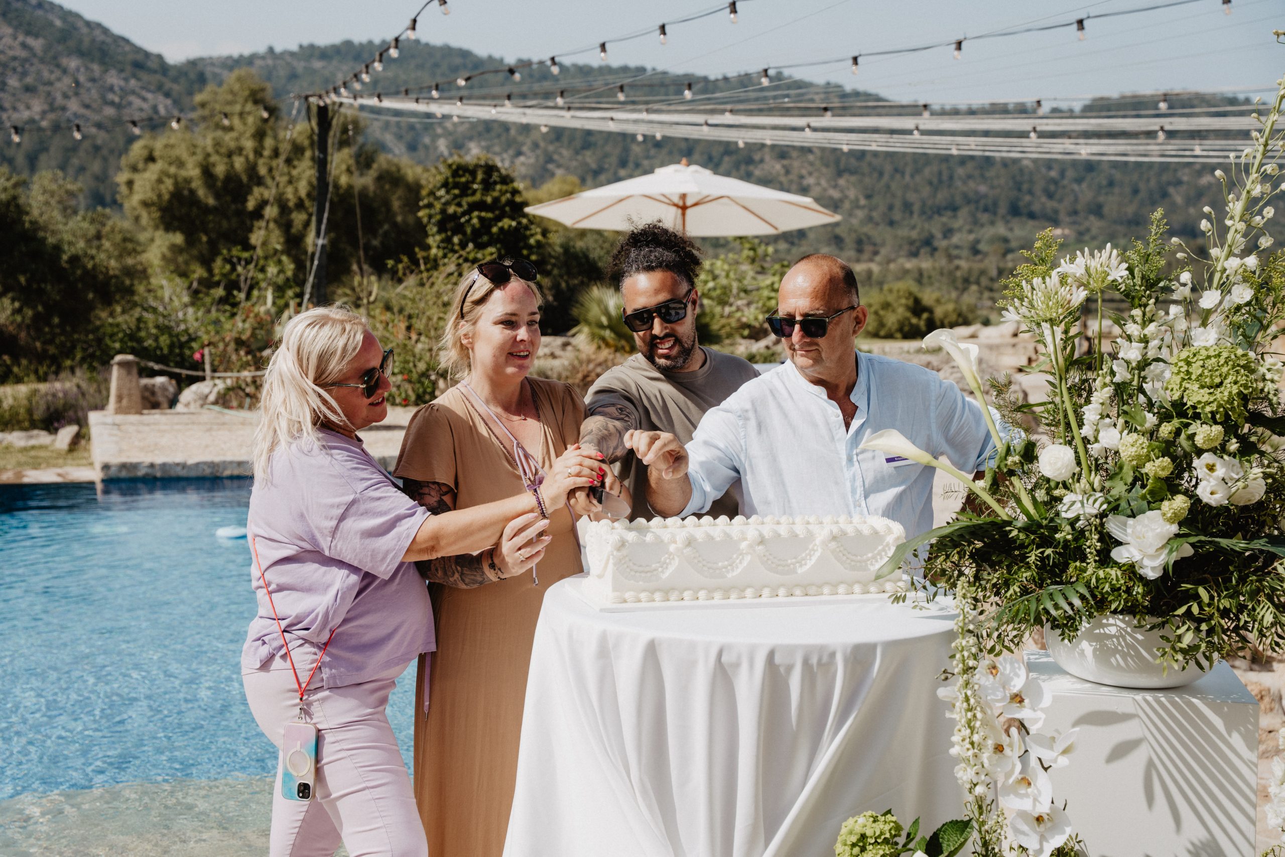 Wedding celebration by the pool at a Mallorca finca — cake cutting moment during a Dybiec Wedding welcome day